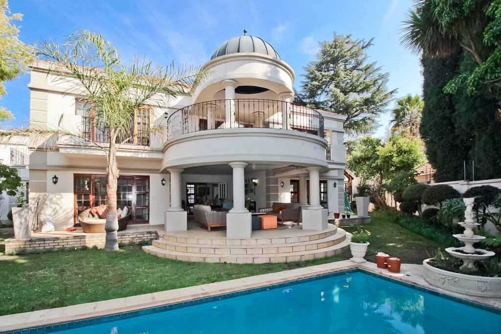 Covered Entertainment patio by pool including pool and well manicured gardens