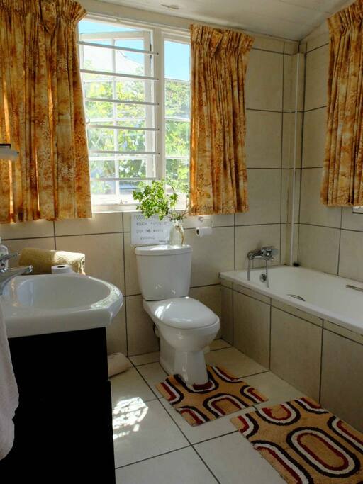 The Garden cottage bathroom that has a toilet, bath with shower and shower.