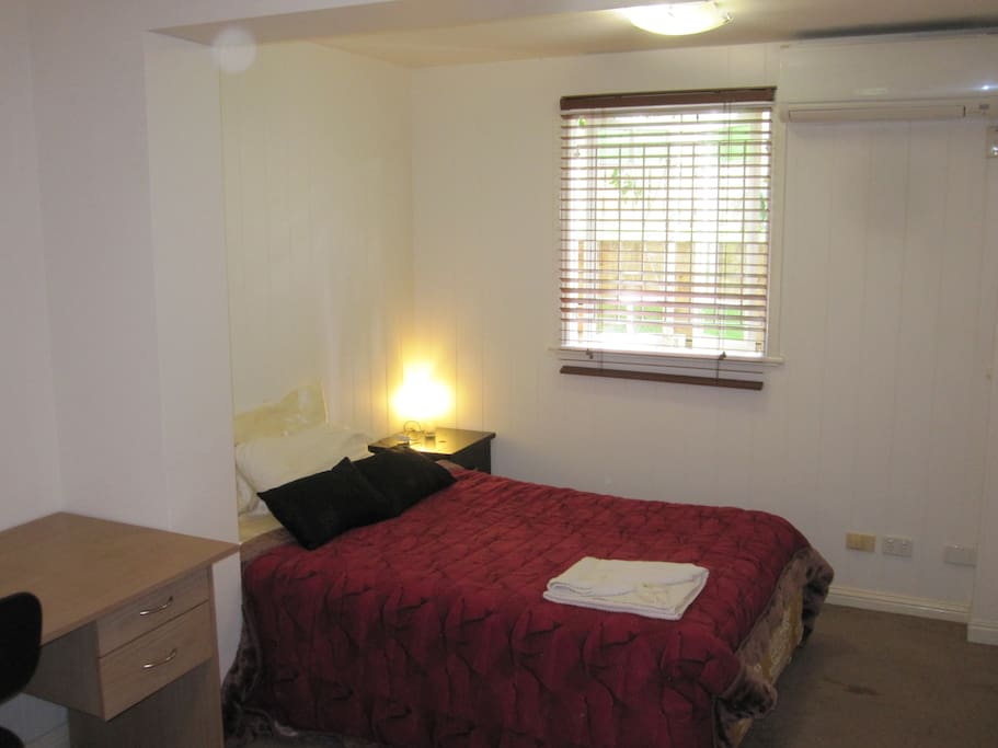 Private bedroom with air conditioning, desk and wardrobe.