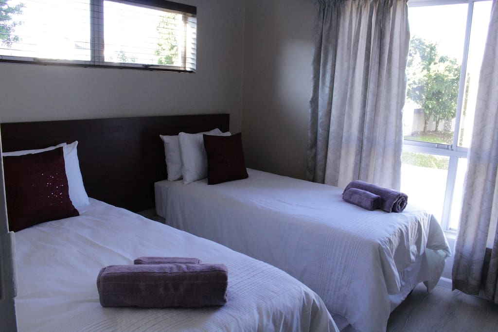 Second bedroom with very good quality beds, wall fan and dark wood built-in cupboards.