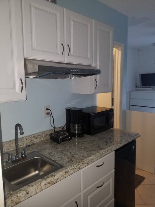 Small kitchenette for light cooking with small fridge, sink, microwave and small burner.