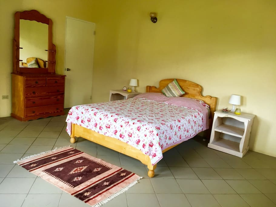 Large bedroom with queen size bed with four windows to let the sea breeze in