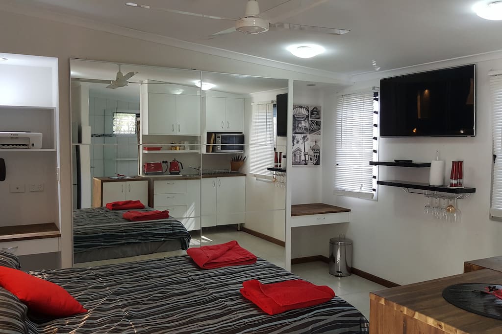 Wall mounted TV, big wardrobe with full-length mirrors, and desks