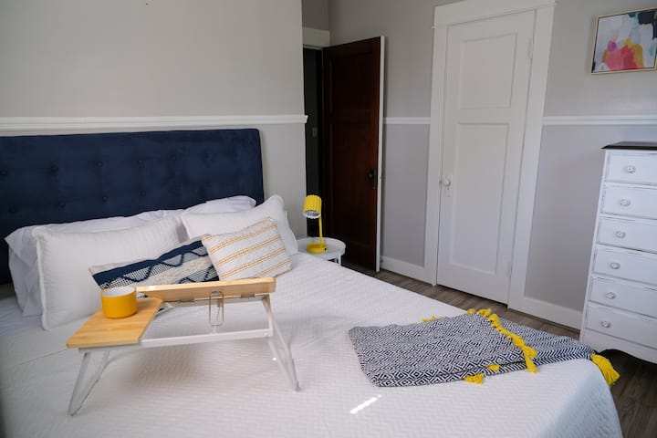 Bedroom 1 features a bold headboard and a lap desk, a funky throw pillow and cozy blanket, a lamp with USB ports for charging your devices, and a large dresser. 