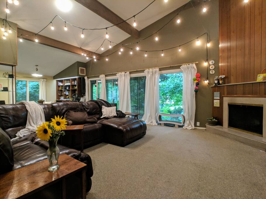Living room with windows facing the ravine, draped lights above, and a comfy couch for watching tv.