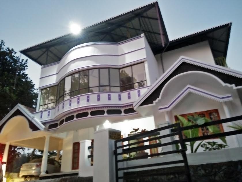 The villa's architectural design features a modern facade with large glass windows, enhancing natural light. A covered porch is visible, along with a landscaped area adorned with plants. The upper floor displays distinct rooflines, reflecting traditional elements integrated with contemporary style.