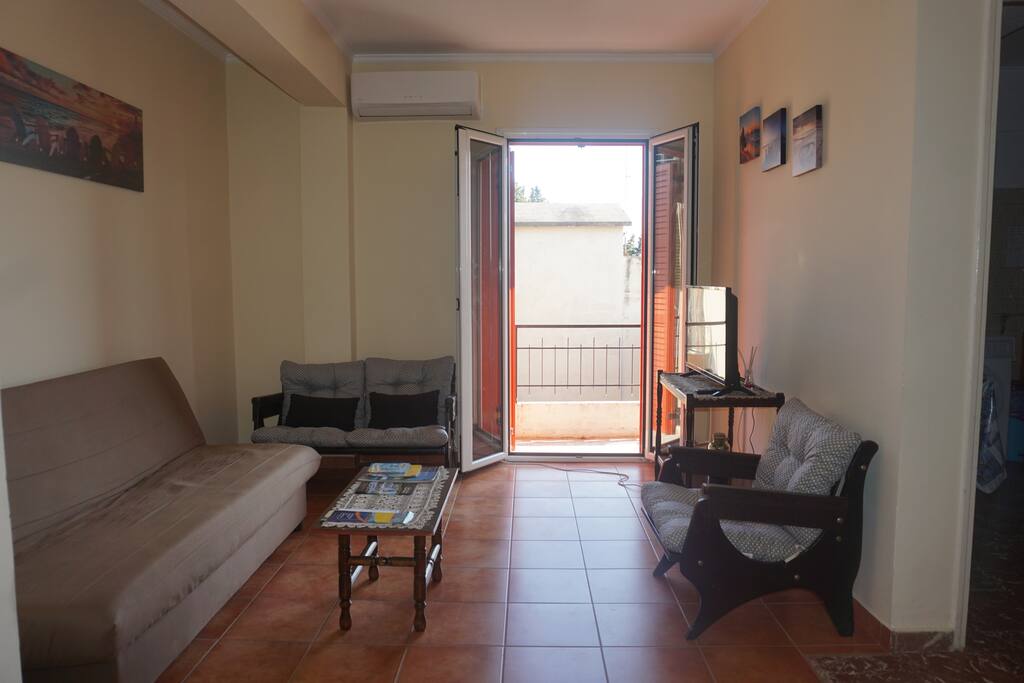 large living room with flat screen tv, sofa, chairs and balcony. Sofa turns into additional bed for 2 more guests (see next picture)