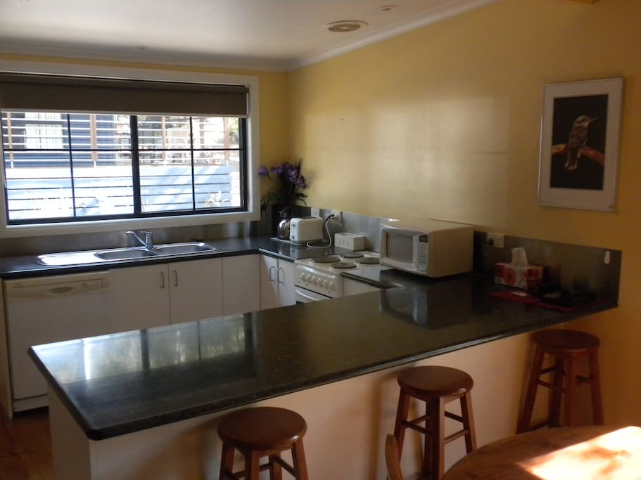 Kitchen with microwave, oven, stove, kettle, toaster, cookware, eating utensils etc