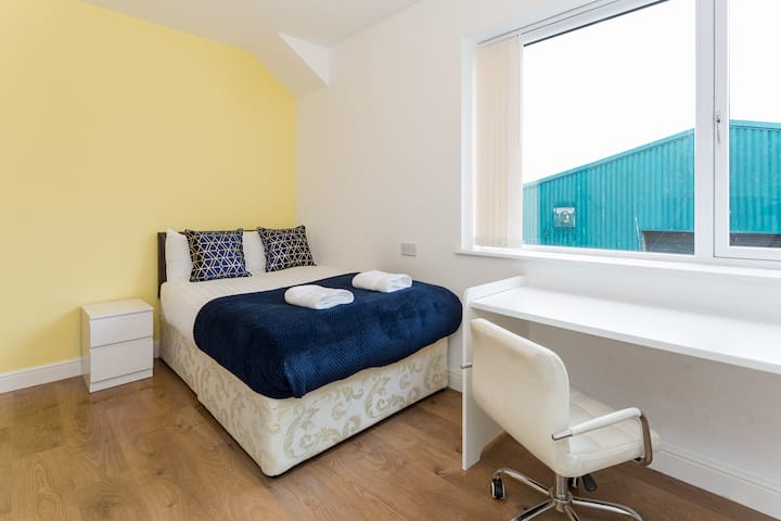 Discover comfort in our corner bedroom, where you'll find a plush bed, crisp linens, and a convenient desk for your work or study needs. The large window floods the room with natural light.