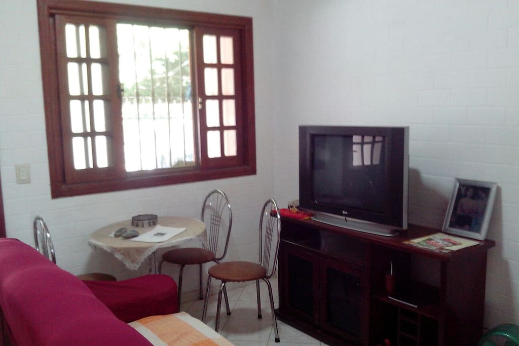 janela da sala com tv sofá e mesa.