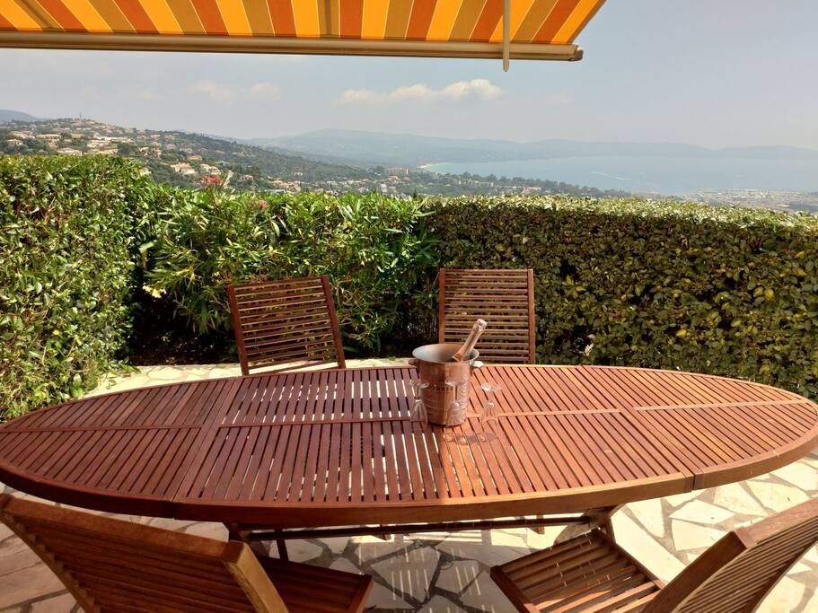 Jardin avec mobilier en teck et store avec vue mer.