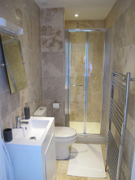 Modern shower room with stone tiled walls and floors.