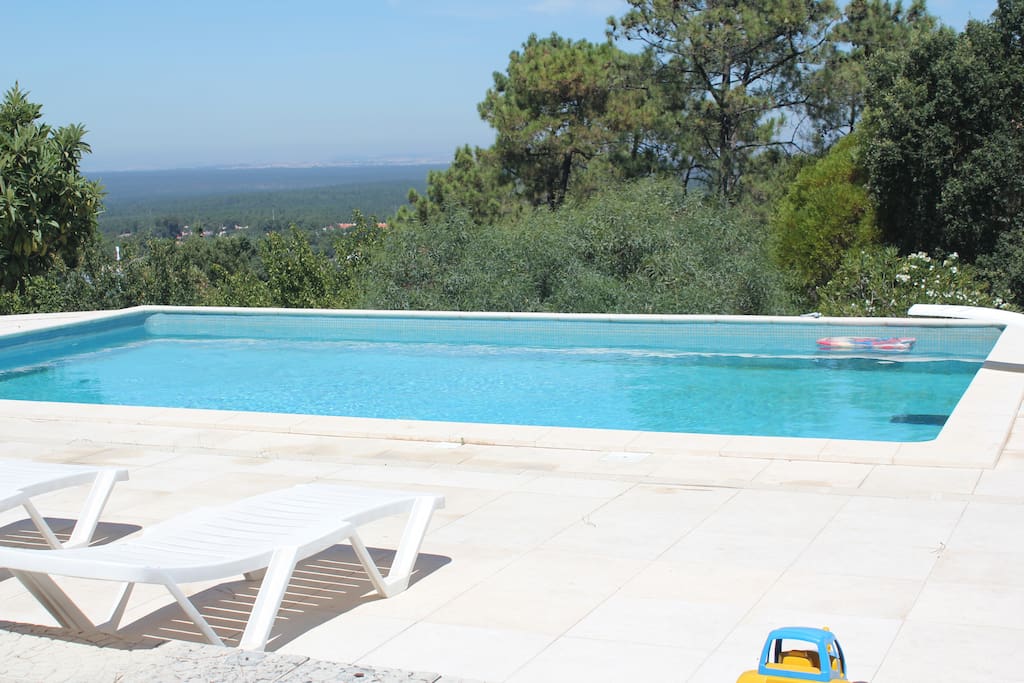 Piscina com paisagem de mar e serra.