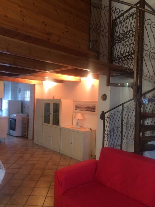Vista dal soggiorno del mobile d'ingresso, della cucina e della scala a chiocciola che porta al soppalco.