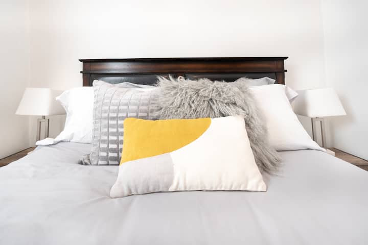 Cama tamaño queen con mesita de noche y lámpara a ambos lados.