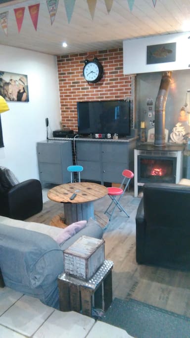 Coin salon en contre-bas avec TV Wifi, un canapé et deux fauteuils