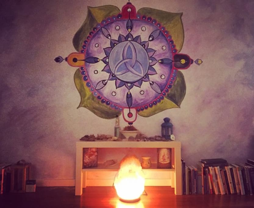 Our cozy living room with hand painted mural, altar space you are welcome to use, salt lamps, and lots of books!
