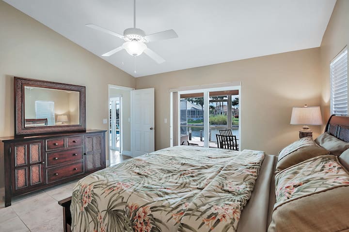 Dramatic king-sized master bedroom with large double windowed doors leading out onto the patio and water. Island living at its finest!