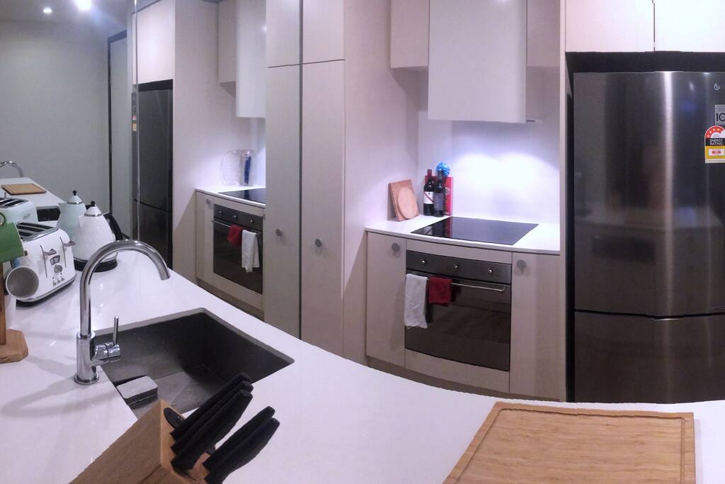 Kitchen with electric stove and oven, dishwasher, toaster, kettle and fridge.
