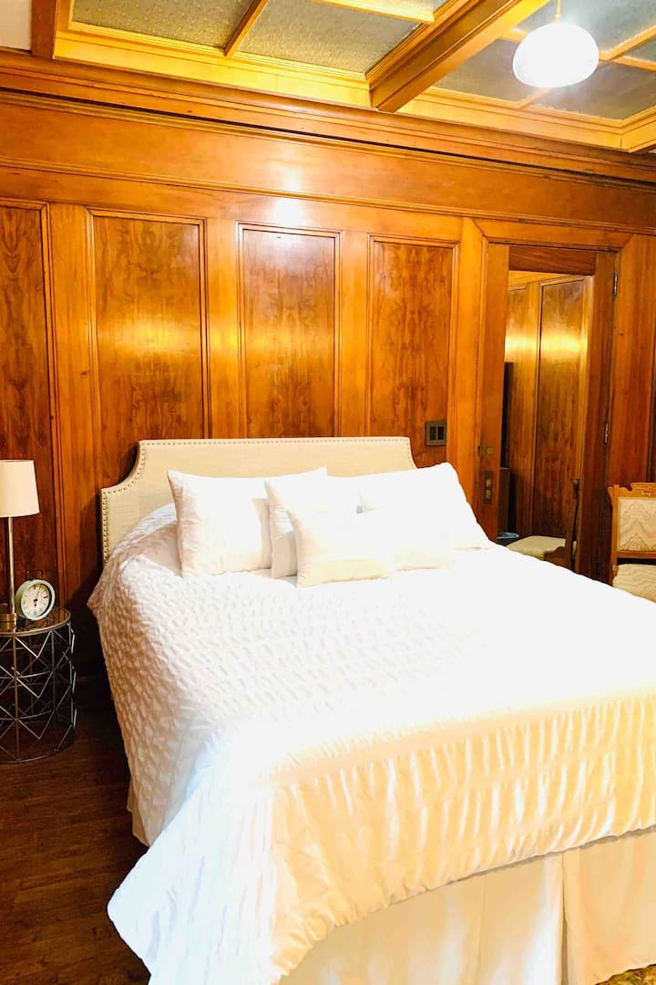 The warm and inviting bedroom features original mahogany paneling and ceiling skylights