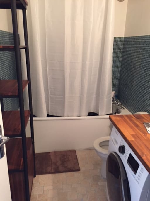 Salle de bain avec baignoire, machine à laver sèche linge