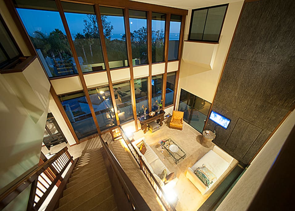 Sunken living room features a massive glass wall of windows showing off the city below.