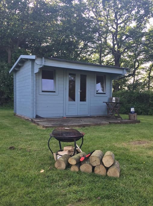 Log Cabin With It's Decking Area And Fire Pit
