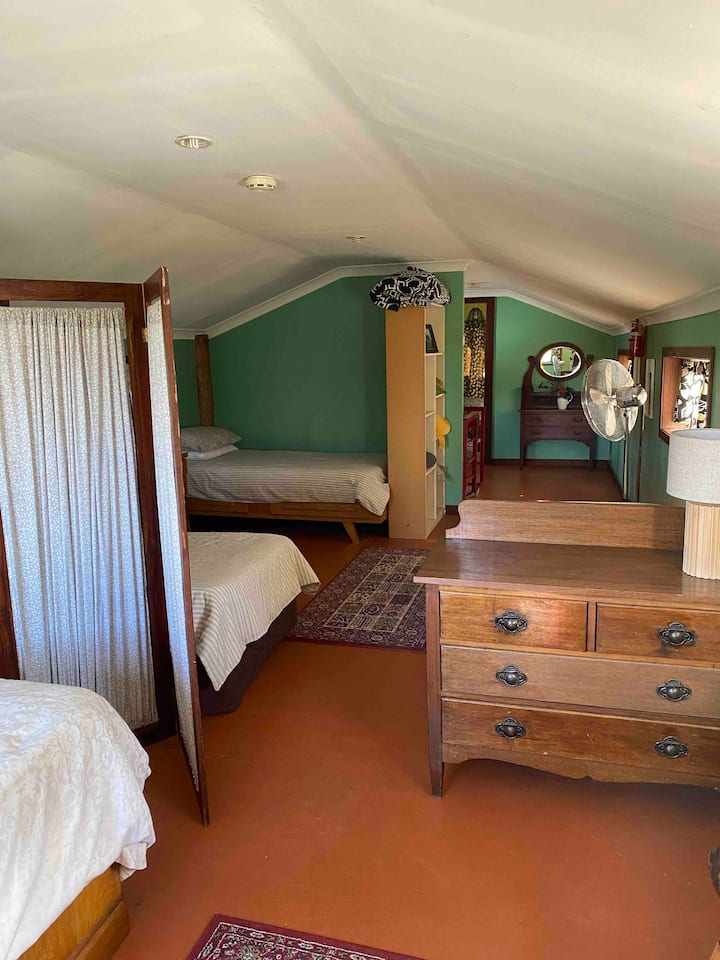 Upstairs there is a large room with a screen dividing three singles beds from a queen bed