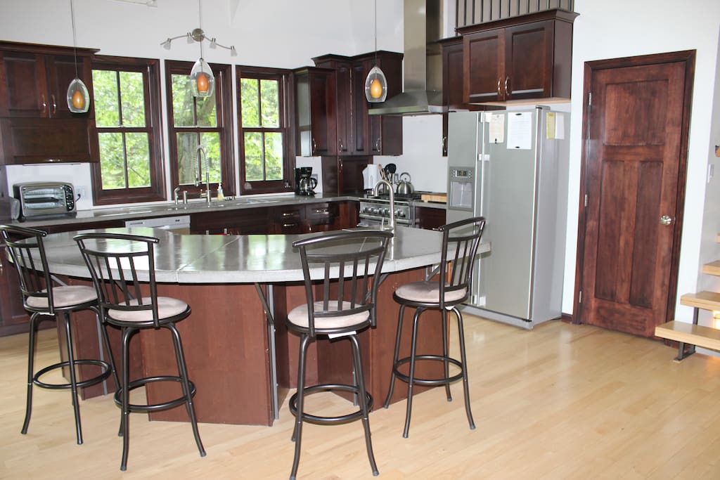 Expansive, custom, gourmet kitchen with immaculate concrete counter tops, a center island with available seating and modern architectural lighting, making it a perfect place for gatherings. The kitchen sits adjacent to the dinning room, seating for up to 10 more people.
