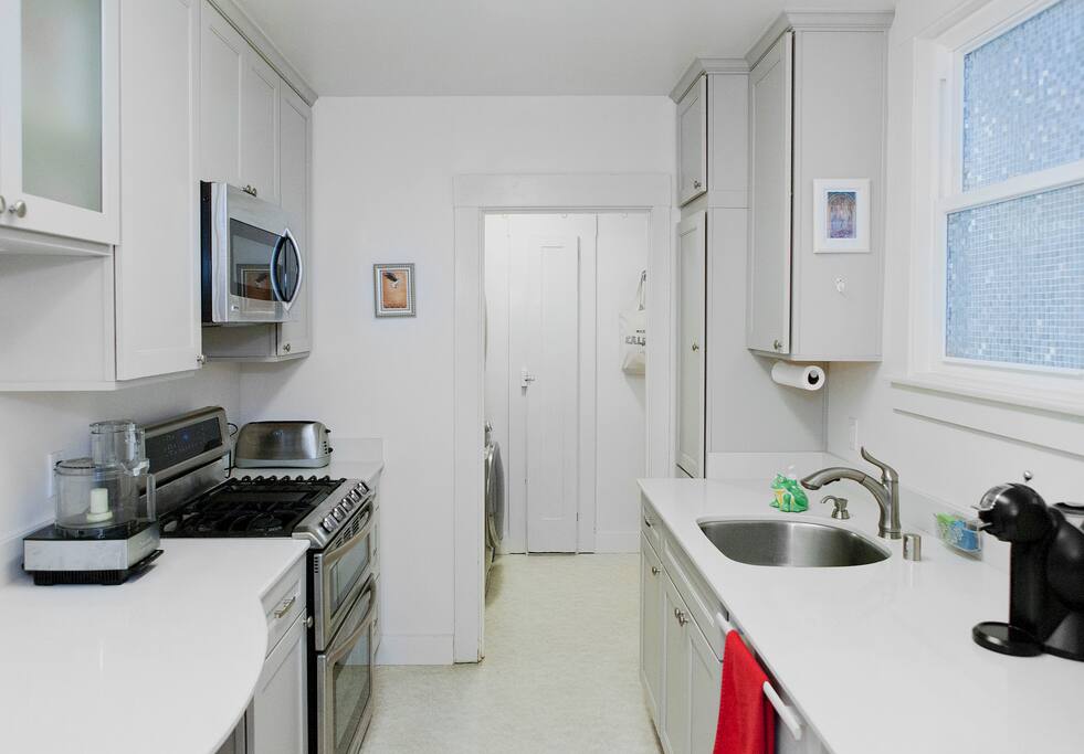 Kitchen with eat-in table, espresso maker, gas stove with dual ovens, built-in microwave, dishwasher. Laundry room in back.