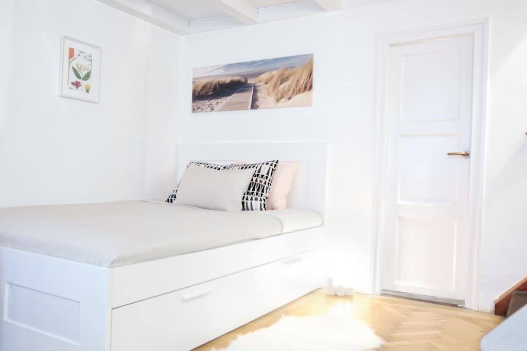 The downstairs bedroom area with queen size bed and storage space underneath.