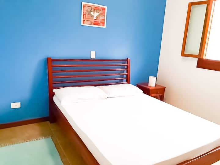 Dvokrevetna plava spavaonica sa stropnim ventilatorom.