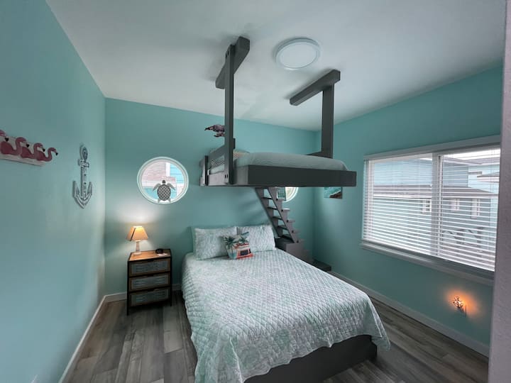 Habitación con literas personalizada para que la usen los huéspedes de cualquier edad. La parte inferior es una cama tamaño queen y la parte superior es doble con una escalera personalizada