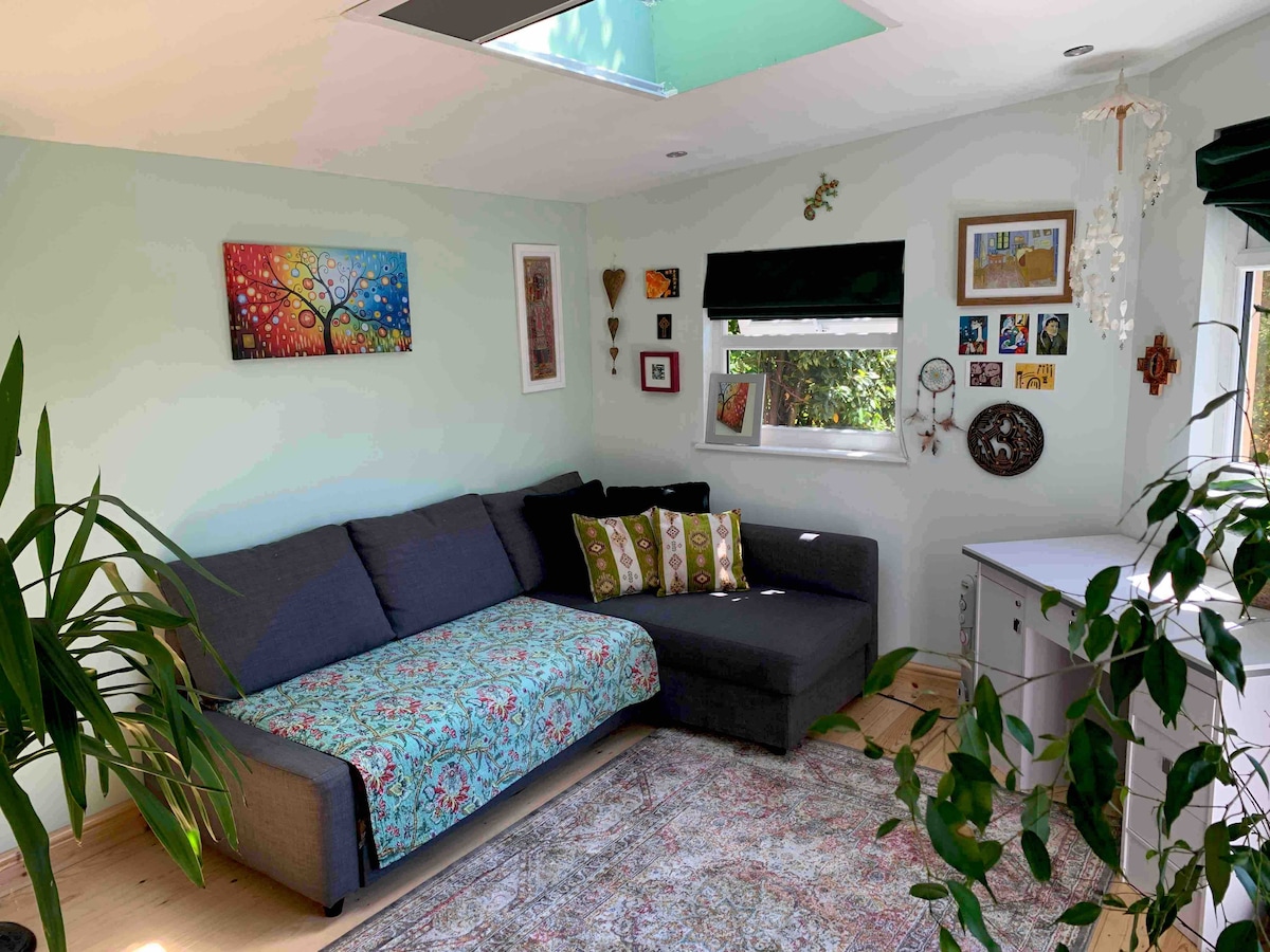 角落沙发床和办公桌。  明亮透气，天窗显示悬垂的树木