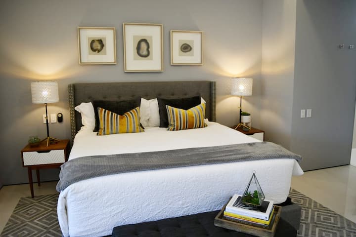 تتميز غرفة النوم الرئيسية بتفاصيل مدروسة مثل تلفزيون ذكي عالي الدقة مع Amazon Prime Video و Alexa Echo وشاحنين لهواتف لاسلكية. يدعوك السرير المريح بحجم كينغ مع غطاء علوي من الإسفنج المرن إلى القفز للحصول على إملائية.