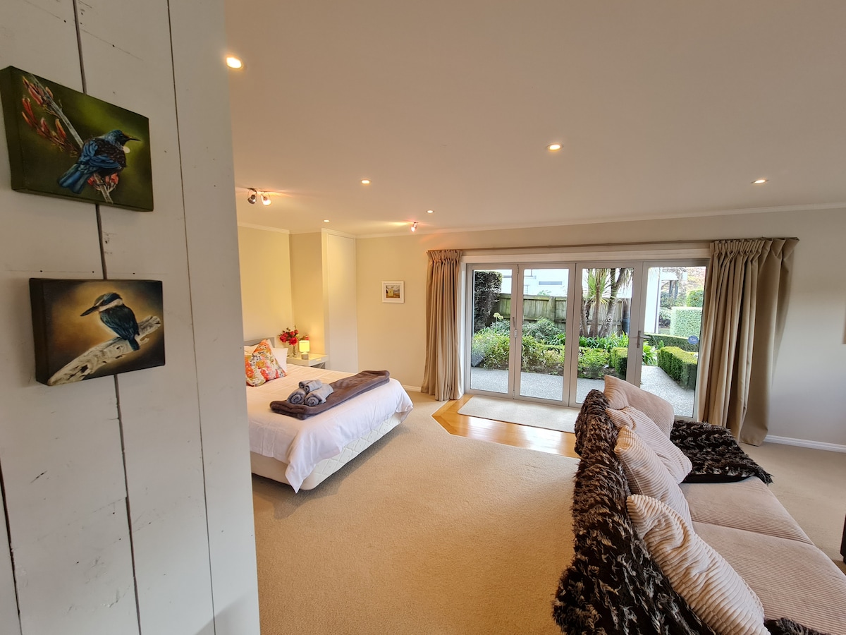 Open plan large space with a Queen bed. Art by Rochelle hangs on the walls, some of which is available for purchase.