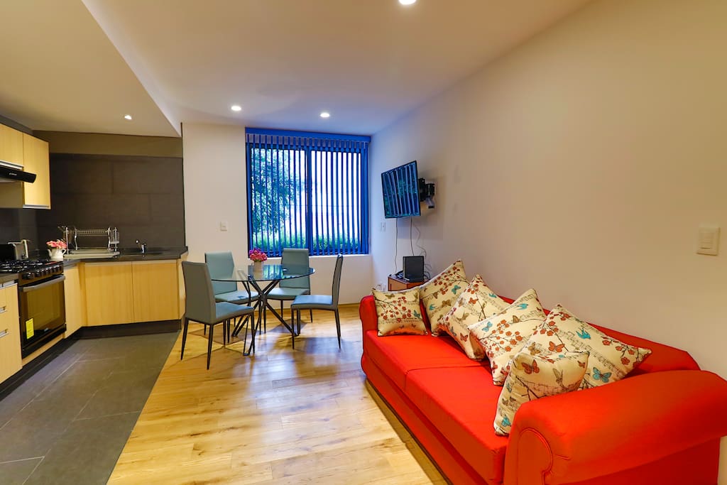 Otra vista de la misma área en donde se muestra el sillón rojo amplio y muy cómodo para ver TV.