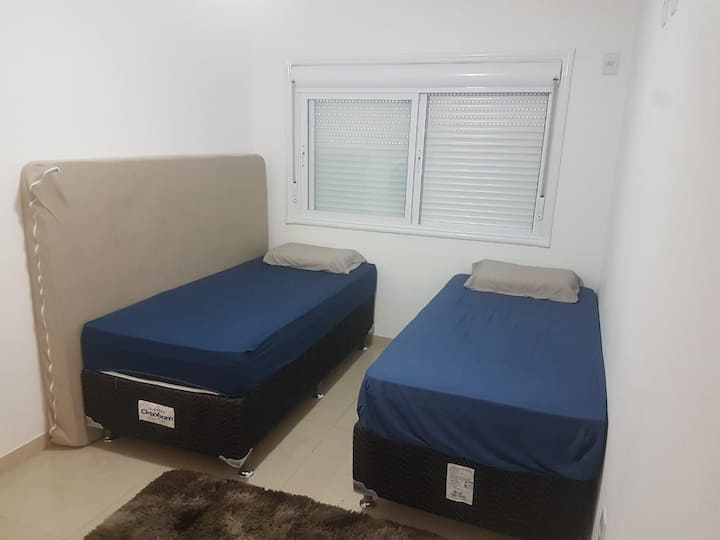 Bedroom with 2 single beds and 1 double mattress and fan.