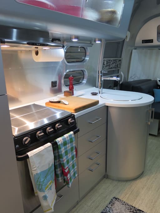 Kitchen with 3 burner stovetop, oven, sink, freezer/fridge and lots of storage
