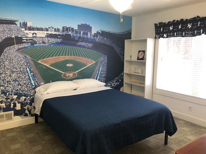Apoya a los Yankees de Nueva York mientras te relajas en esta cama tamaño queen en este dormitorio de invitados del segundo piso.