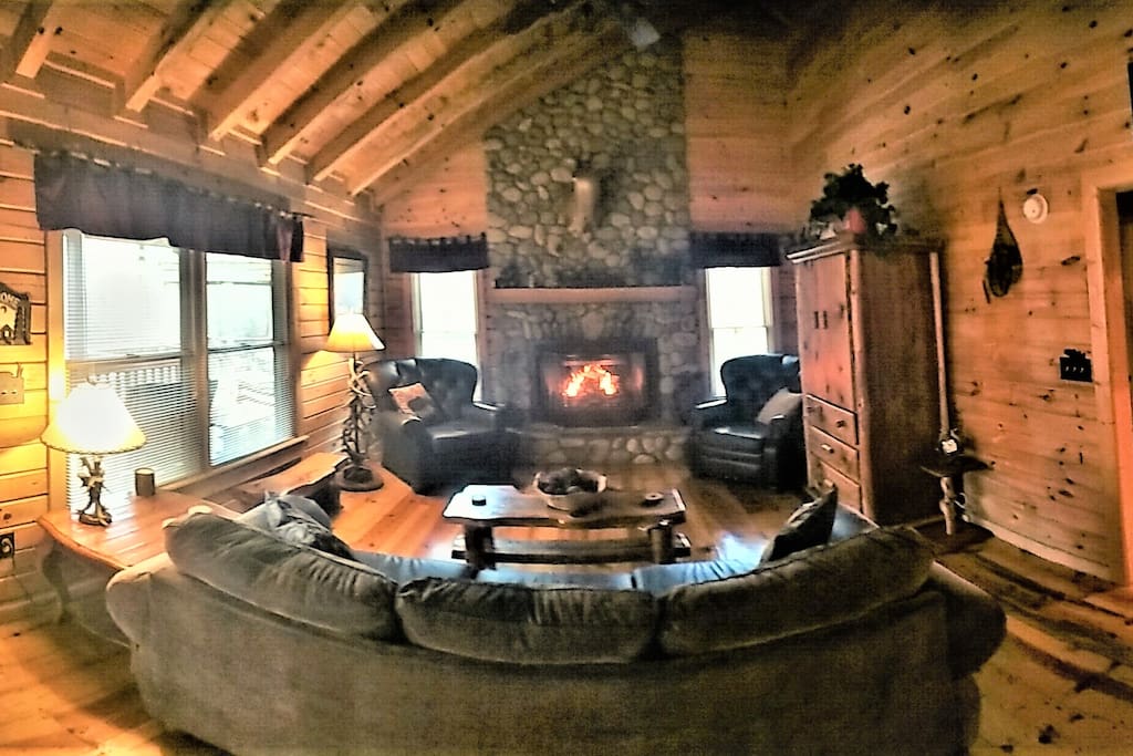 Great Room with a real wood burning fireplace, beautiful decor, loft, and large flatscreen TV.