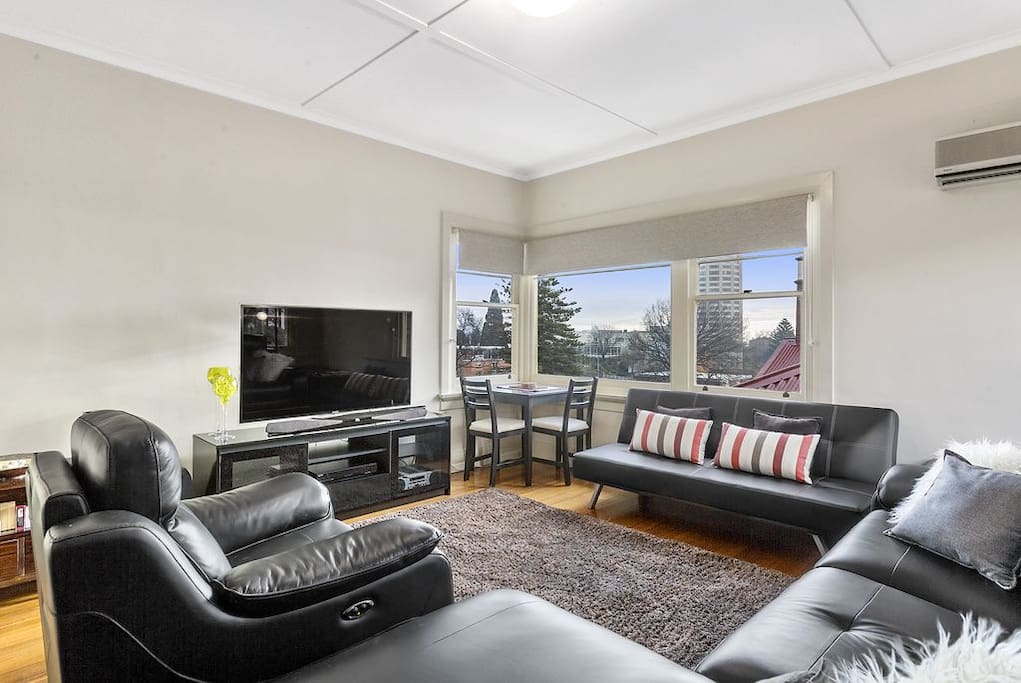 Living room with a stunning view of Wrest Point Casino, modern television, heat pump and electric recliner couches...
