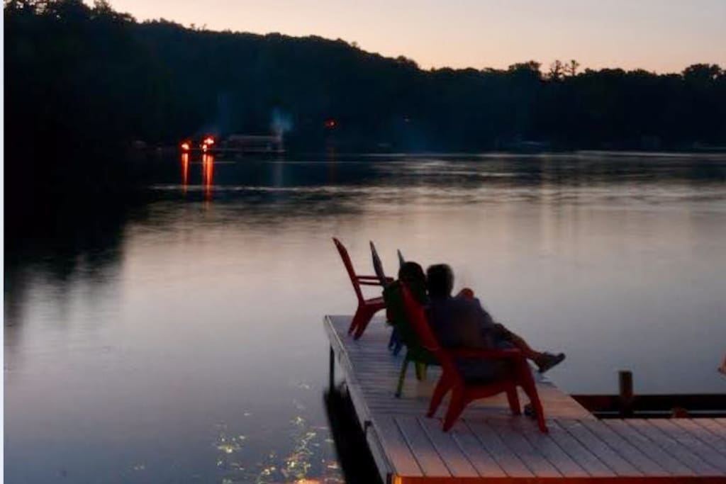large lakeside deck and dock with floats, sand toys, chairs and picnic table.