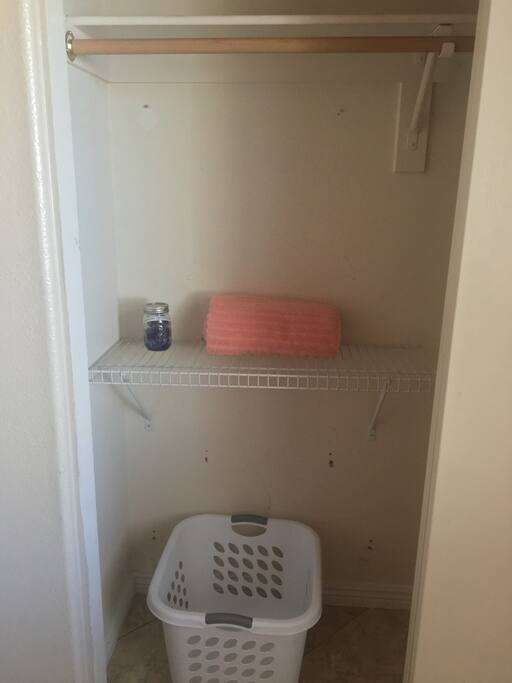 Closet with hangers, laundry detergent, bath towels, laundry basket and shelf space.