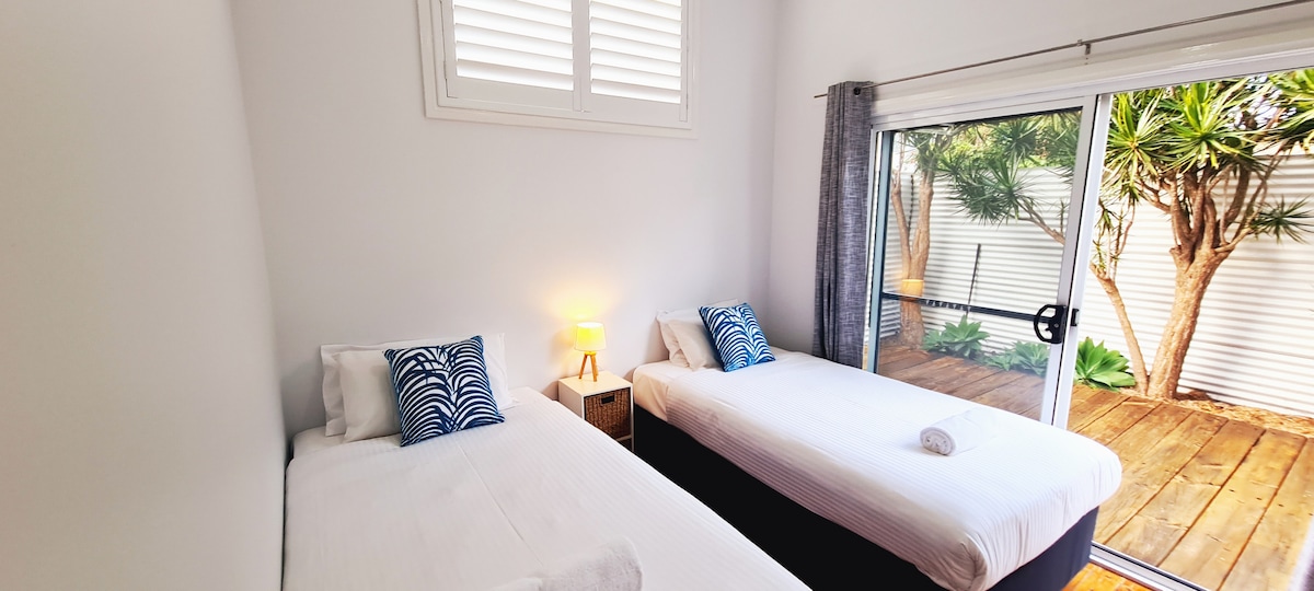 Spálňa s oddelenými posteľami s manželskou posteľou, stropným ventilátorom, vstavanou skriňou a posuvnými dverami na zadný dvor