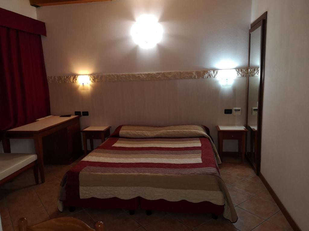 A cozy sleeping area is featured, with a spacious bed adorned in a striped blanket. Warm lighting emanates from wall fixtures, reflecting off neutral walls. A small table and two chairs are positioned in the corner, contributing to the overall functionality of the space.