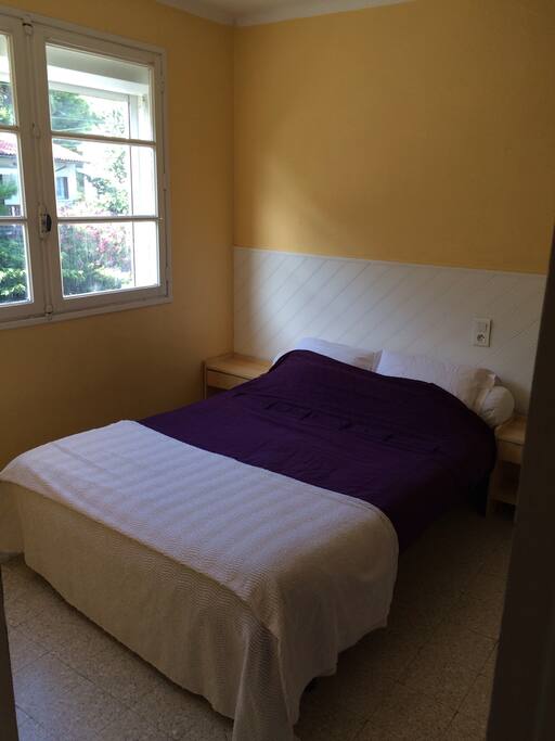 Chambre d'une dizaine de m2 avec un grand lit et une armoire sur le côté