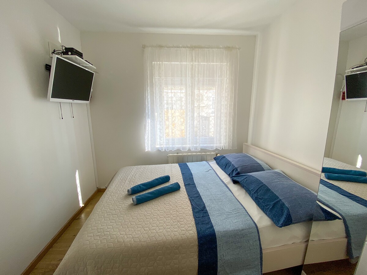 Spavaća soba s bračnim krevetom i televizorom.