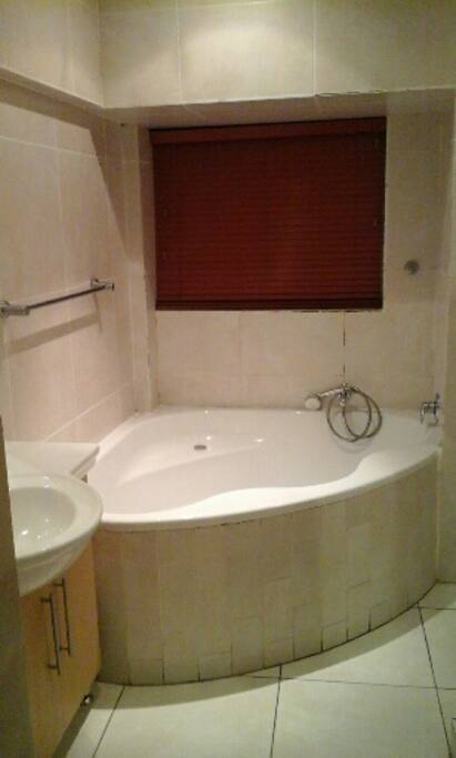 Corner bath with shower hand basin and toiletries cupboard