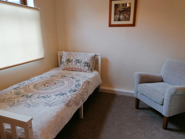 Cosy Single bedroom with comfortable chair and chest of drawers. 